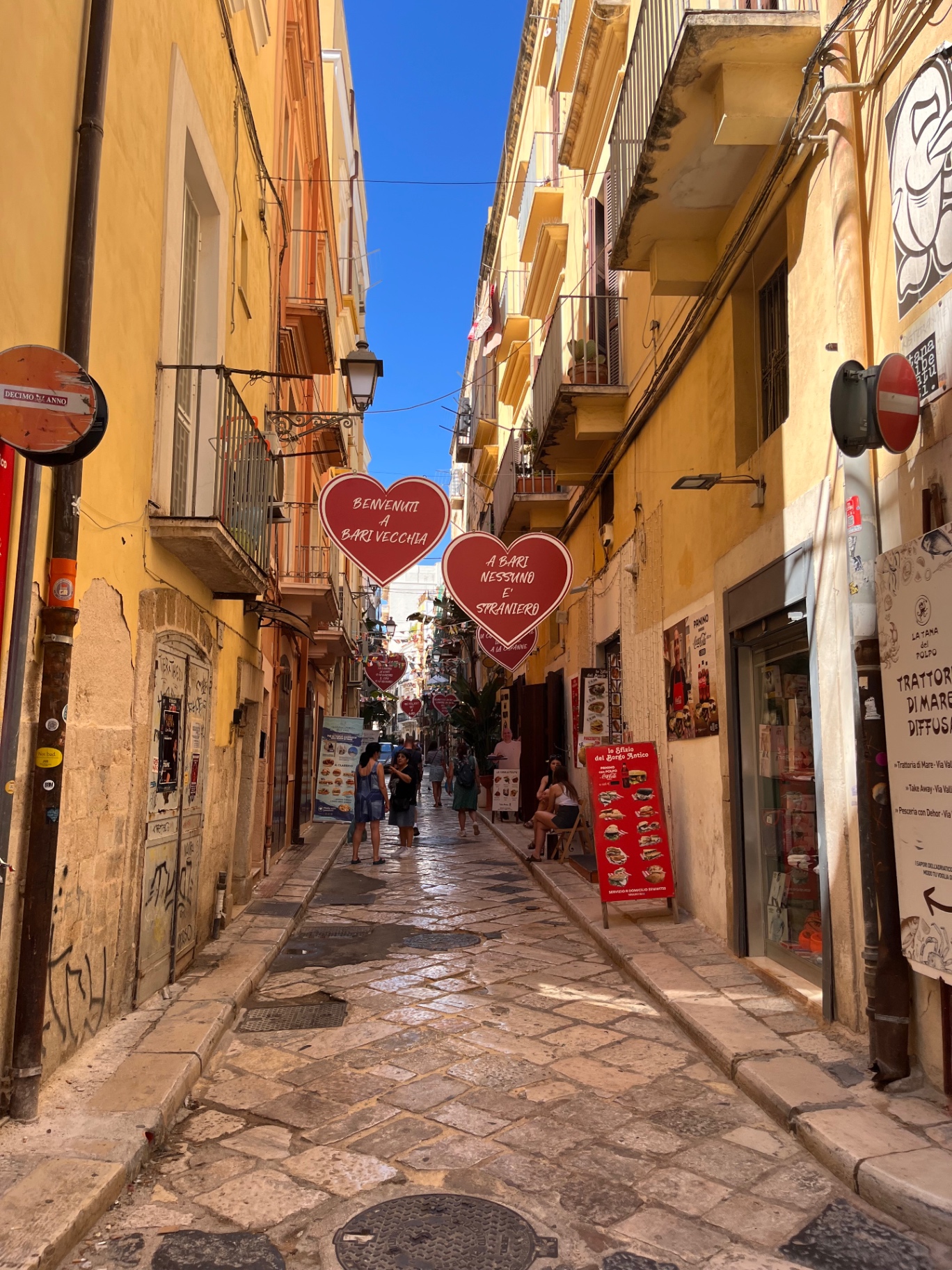 Ruelle de Bari Vecchia en Italie, des cœurs rouges suspendus portant l'accueil « A Bari nessuno è straniero »